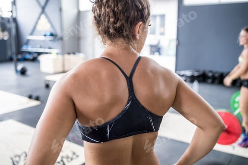 Preview: back view young sportive athletic fitness woman sweating training intense gym workout