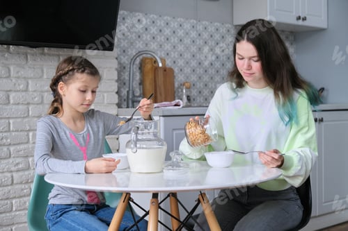 Preview: Girls having breakfast sitting at table in home kitchen