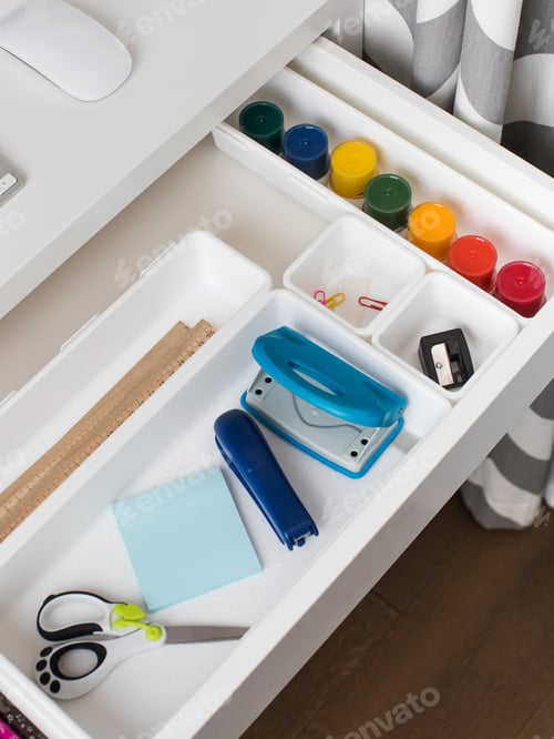 Preview: Office supplies are laid out in a white plastic container in the shelf of the desk. Back to school.