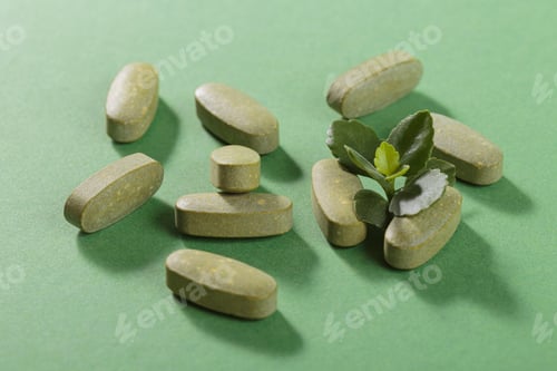 Preview: Herbal and Vitamin Green pills freely laid on green background