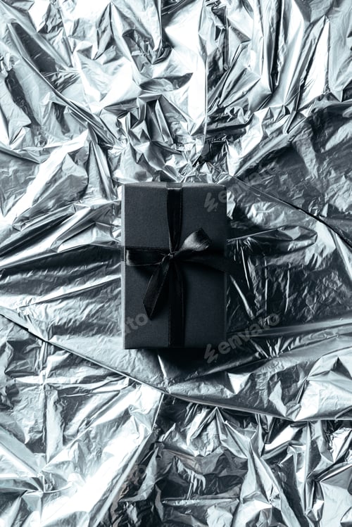 Preview: top view of gift box with black ribbon on silver wrapping paper backdrop