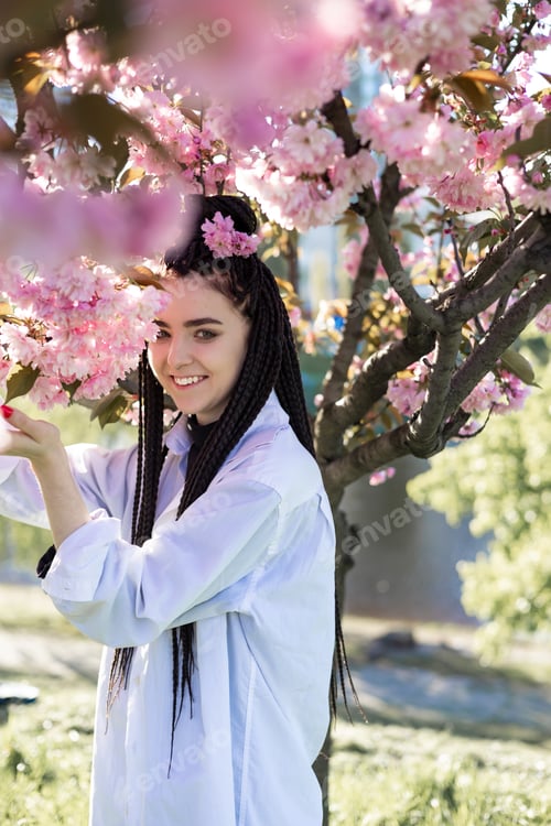Preview: beautiful young teen girl in spring blooming cherry blossoms garden