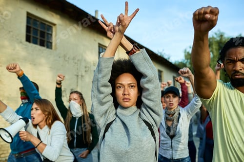 Preview: African American woman with arms above head showing peace gesture on a protest.
