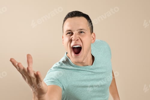 Preview: Handsome young man shouting on beige background