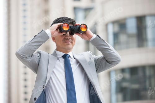 Preview: Confident businessman looking through binoculars