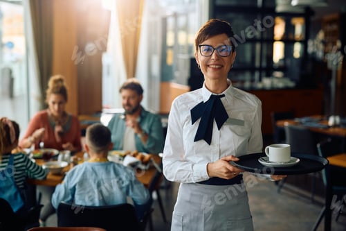 Preview: Happy waitress in hotel restaurant looking at camera.