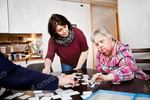 Preview: Healthcare worker assisting women with down syndrome in arranging cards at table