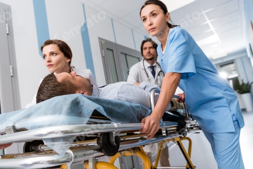Preview: Doctors and nurse transporting unconscious patient on gurney