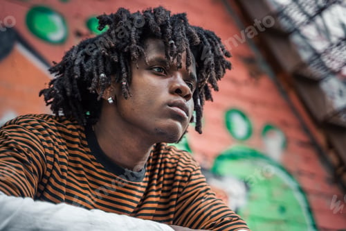 Preview: Portrait of young handsome stylish black man with natural hair dreadlocks. Afroamerican guy. Stairs,