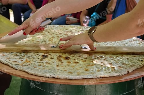 Preview: Womans hands cutting soparnik - traditional Croatian food on big wooden plate