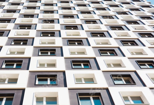 Preview: Modern and new apartment building. Photo of a tall block of flats against a blue sky. Close up.