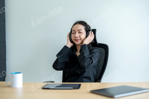 Preview: Businesswoman listening music relaxing at workplace in office