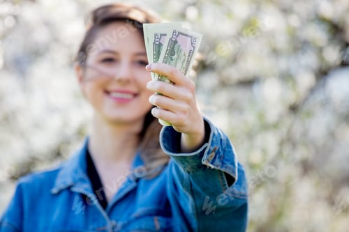 Preview: girl in a denim jacket and money stands near a flowering tree