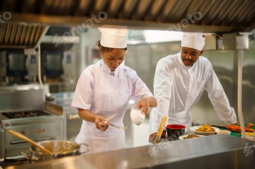 Preview: Two chefs in white uniforms working together in a busy restaurant kitchen preparing food