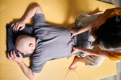 Preview: Masseuse making thai yoga massage. Woman therapist doing traditional massage treatment for patient.