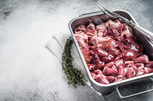Preview: Raw chicken offals meat set, gizzards, stomachs, liver and hearts in a steel tray with herbs