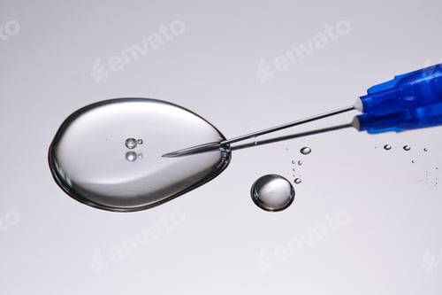 Preview: A drop of medicine flowing from a syringe with a needle.