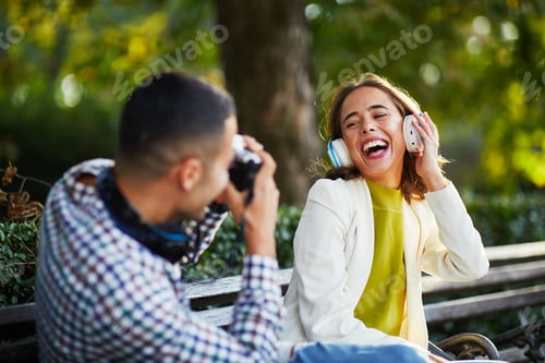 Preview: Young man photographing young woman with headphones for social network