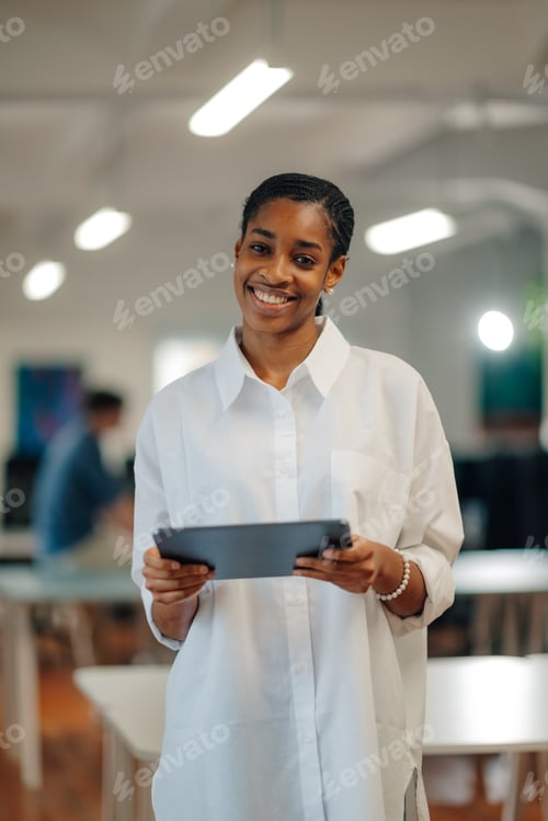 Preview: Smiling black businesswoman holding digital tablet in modern office