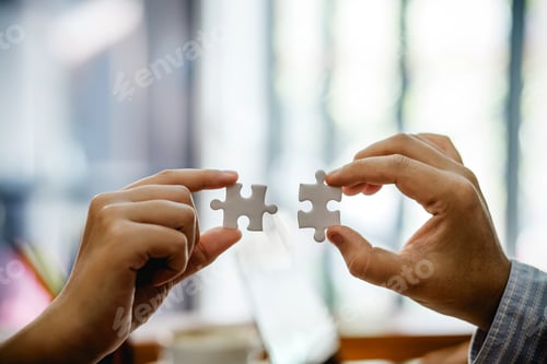 Preview: Close-up of businessman and businesswoman jigsaw puzzles together at office.