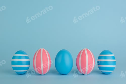 Preview: Five Easter blue and pink eggs with white stripes on blue background.