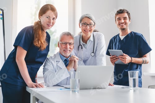 Preview: Portrait of positive medical professionals standing in clinic boardroom and and looking at camera