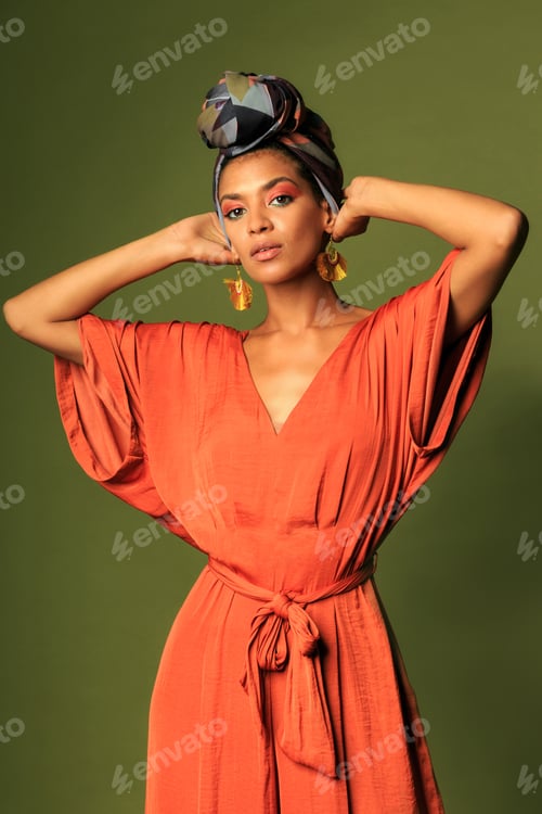Preview: Young black african woman wearing orange dress with turban and ethnic jewelry