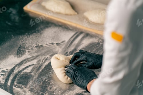 Preview: a female chef's hands carefully kneading dough for preparing and baking bread in a bakery