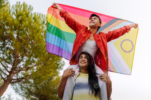 Preview: Happy non-binary couple celebrating lgbtq pride with LGBTQIA flag