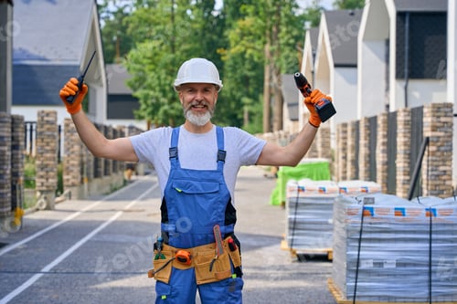 Preview: Joyful building contractor posing for camera on construction site