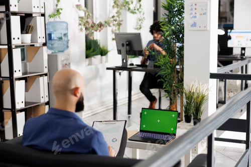 Preview: Executive analyzing reports and using laptop with green screen.