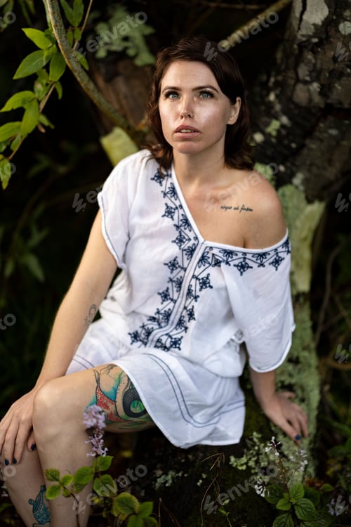 Preview: woman sitting on the ground looking off to the side wearing a dress