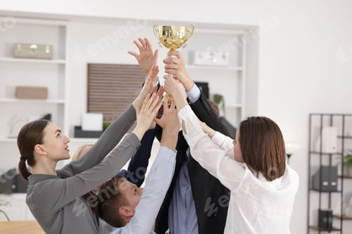 Preview: Competition concept. Group of businesspeople with golden trophy in office