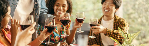 Preview: Group of happy young friends is drinking wine while having holiday dinner home party together