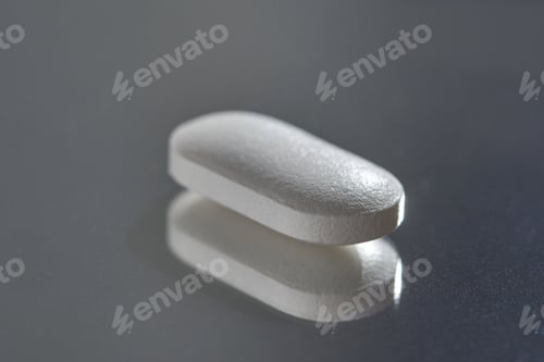 Preview: Close-up of white pill on reflective surface highlighting medicine