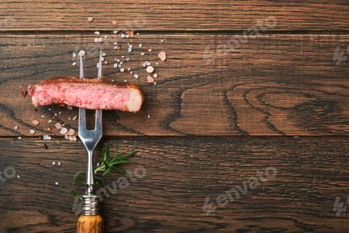 Preview: Steaks T-bone. Slices of beef grilled meat barbecue steak on meat fork on burned dark wooden backgro