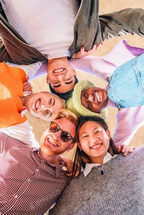 Preview: Vertical low angle view of a multiracial happy young friends having fun and looking at camera
