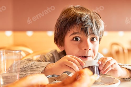 Visualização: menino de idade elementar com bigode de chocolate bebendo chocolate quente
