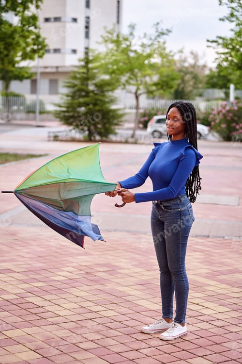 Preview: African American woman opening an umbrella outdoors on the street.