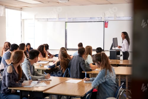 Preview: Female High School Teacher Standing By Interactive Whiteboard Teaching Lesson