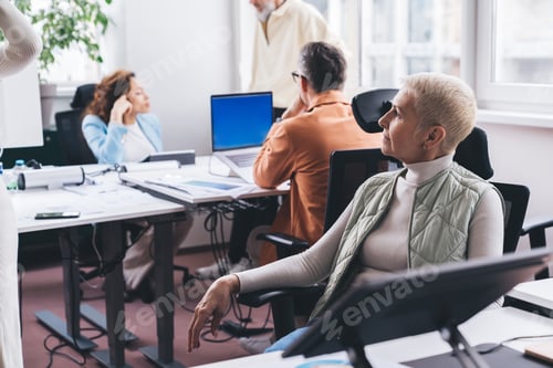 Preview: Female entrepreneur looking at coworkers in office
