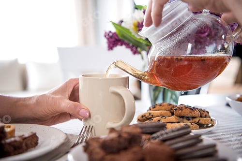 Preview: cropped shot of man pouring tea into cup during breakfast at home