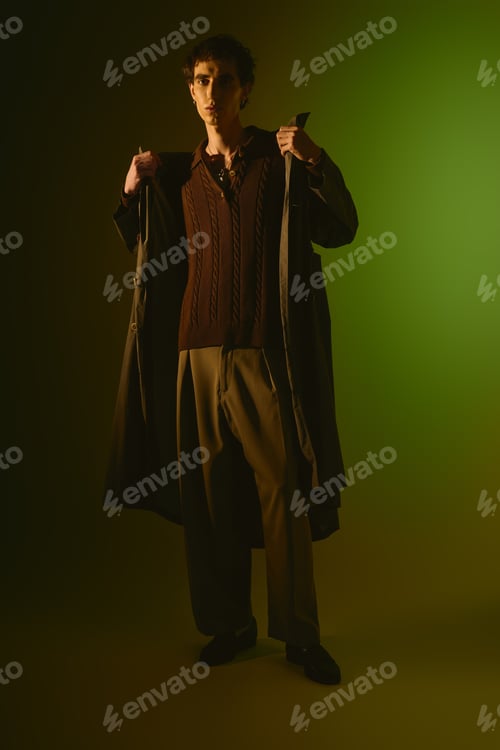 Preview: Handsome young man in stylish attire showcased against a vibrant green backdrop