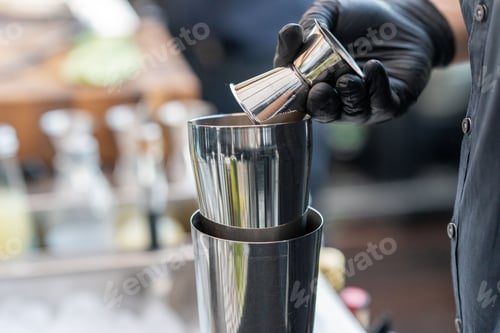 Preview: Bartender pours a cold beverage into a bar mixer.