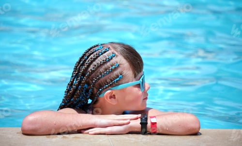 Preview: Young joyful child girl resting on swimming pool side with clear blue water