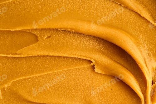 Preview: Macro of american peanut butter smear smooth nutty brown texture. Keto diet ingredient