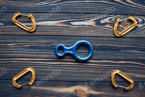 Preview: Isolated photo of climbing equipment. Parts of carabiners lying on the wooden table