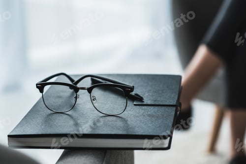 Preview: Close-up view of glasses on notebook in front of female patient