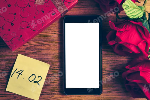 Preview: Smart phone with blank screen, gift box and red roses on wooden table. Concept of Valentine Day.