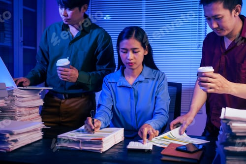 Preview: Three young businessmen work together in office at night, busy on their laptops,checking documents